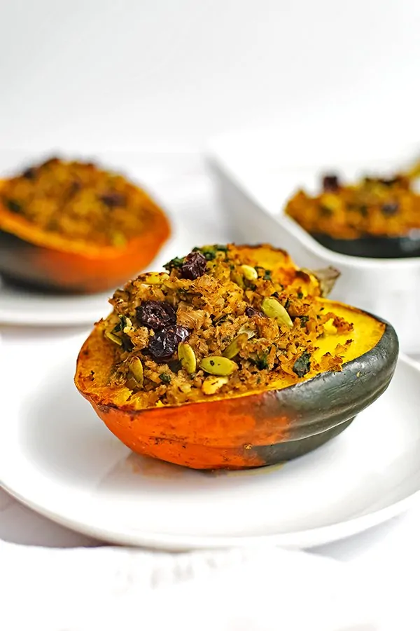Stuffed acorn squash recipe on a white plate with a second acorn squash in the background