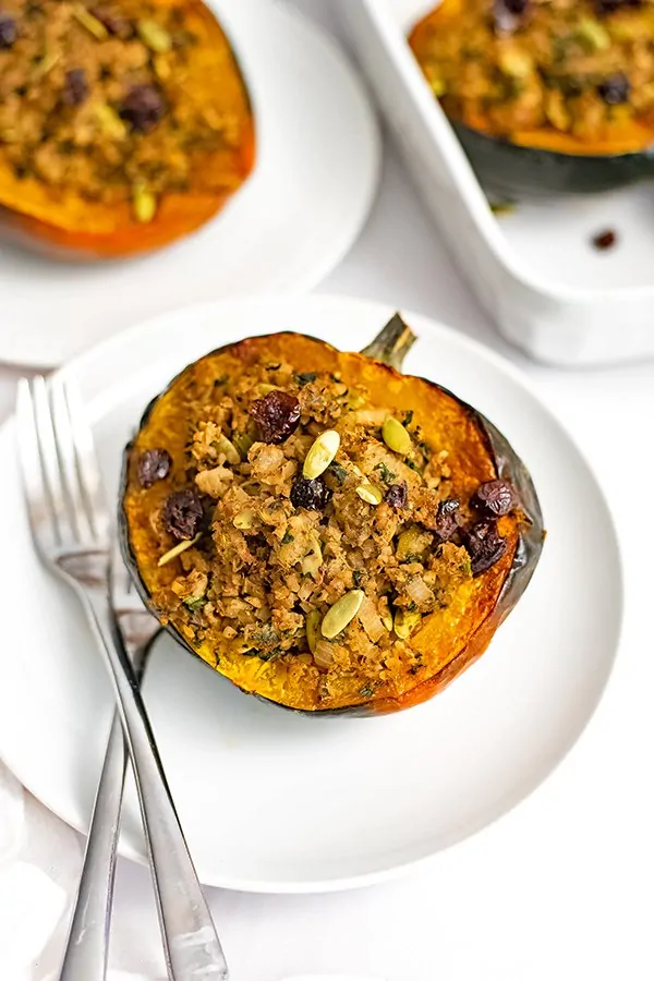 Overhead shot of stuffed acorn squash recipe on a white plate with two forks on the plate