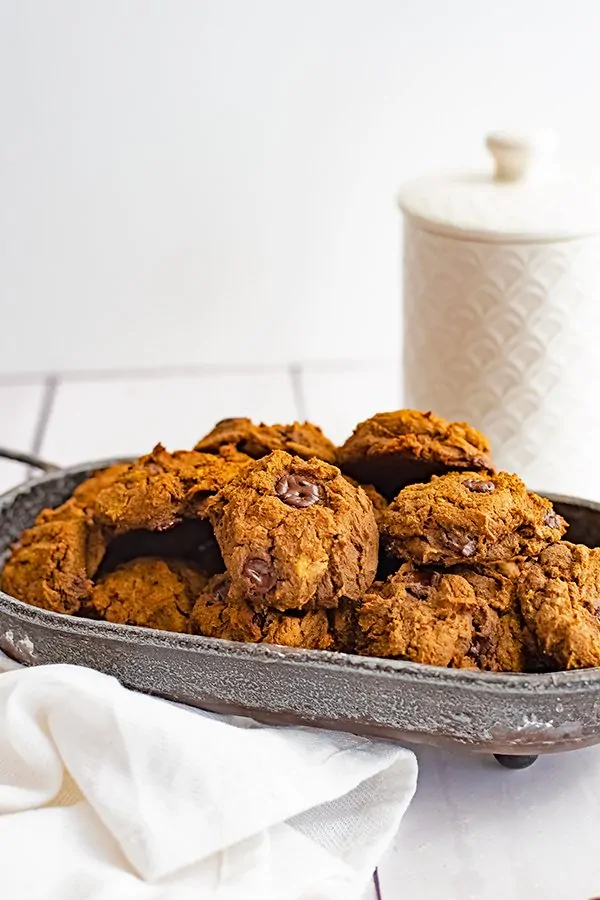 Metal basket filled with butternut squash chocolate chip protein cookie recipe with a white cookie jar in the background