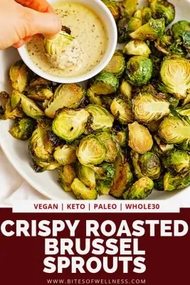 Large plate filled with crispy roasted brussel sprouts with garlic dijon sauce with a brussel being dipped into the sauce with pinterest text at the bottom of the photo