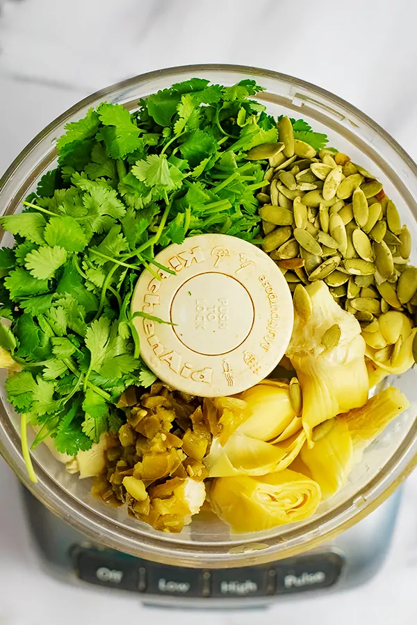 Food processor filled with jalapeno cilantro hummus ingredients