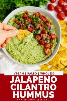 Overhead shot of bowl filled with jalapeno cilantro hummus with a plantain chip dipping into the hummus with pinterest text on the bottom