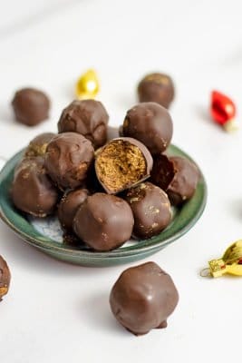 Green plate filled with gingerbread truffles surrounded by brightly colored ornaments.
