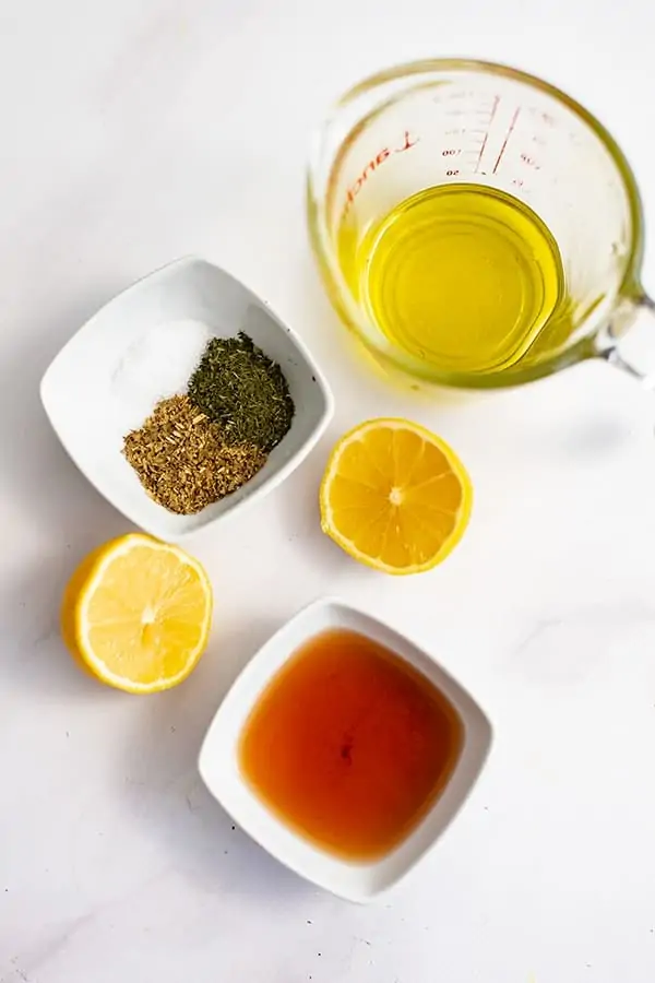 Ingredients for greek chicken marinade in bowls on a marble table
