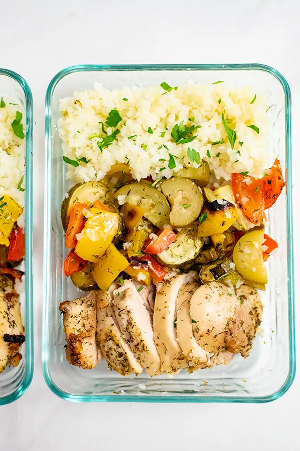 Glass pyrex container filled with greek chicken marinade sheet pan dinner for meal prep