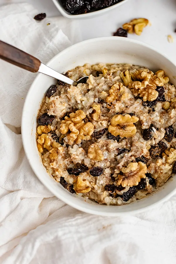 White bowl filled with Walnut Cranberry High Protein Oatmeal with a spoon 