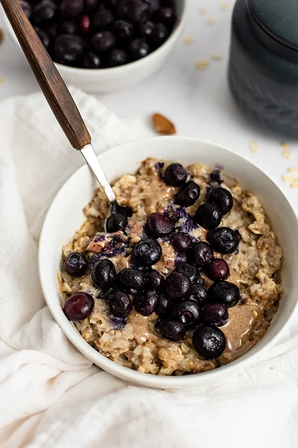 White bowl filled with Blueberry Almond High Protein Oatmeal with a spoon