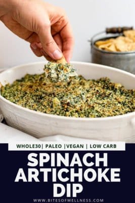 White casserole dish with whole30 spinach artichoke dip with a hand dipping a chip into the spinach artichoke dip. Pinterest text on the bottom