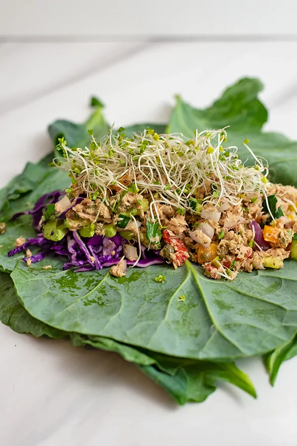 Healthy Mediterranean tuna salad (no mayo) on a collard green wrap with red cabbage and sprouts 