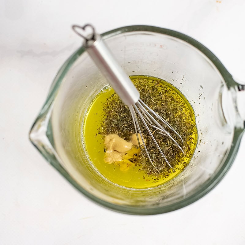 Ingredients to make lemon dressing in a glass measuring cup.