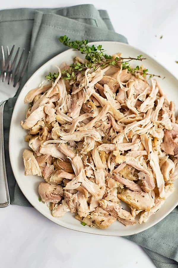 White plate filled with Instant Pot Shredded Chicken Thighs with fresh thyme