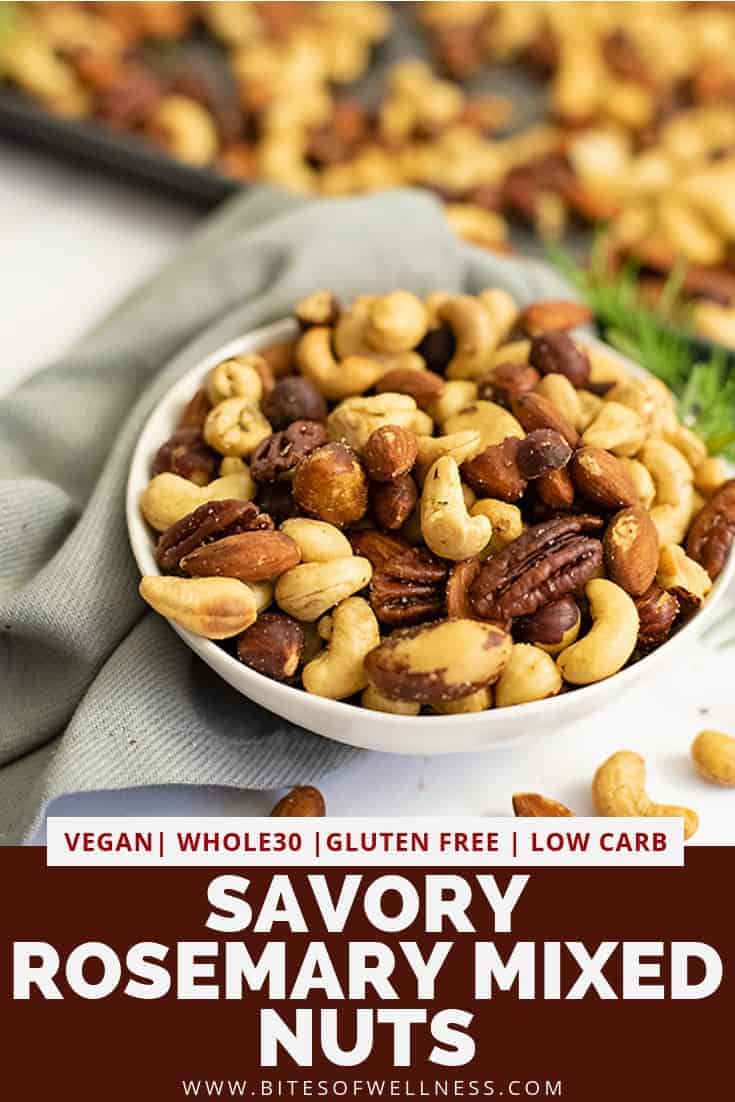 Close up on a white bowl filled with rosemary savory spiced nuts with a grey napkin and baking sheet full of nuts in the background with pinterest text on the bottom of the photo