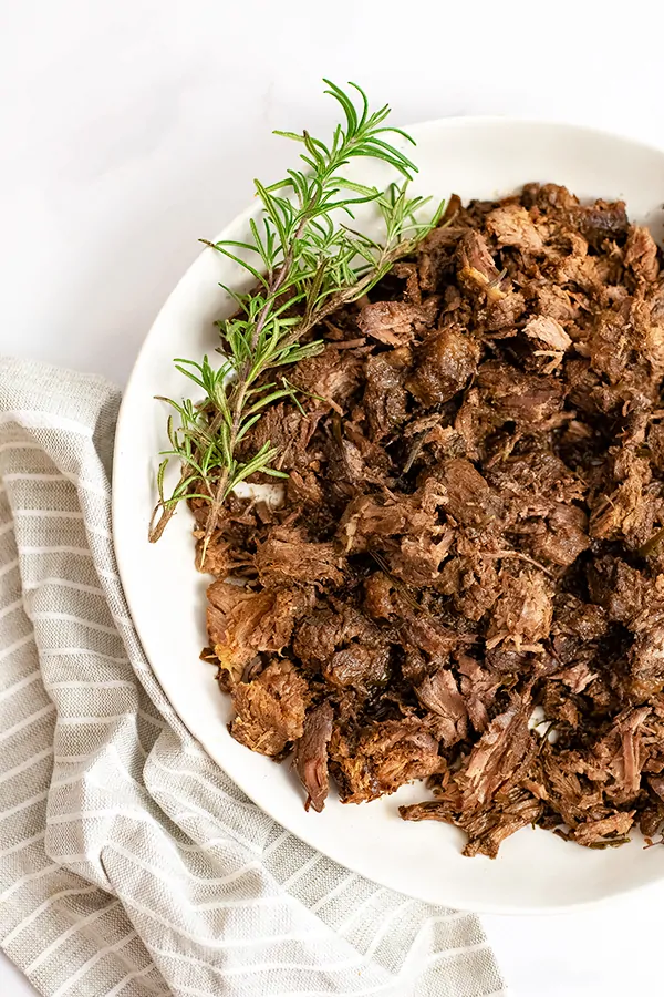 arge bowl filled with slow cooker balsamic beef over a brown striped napkin