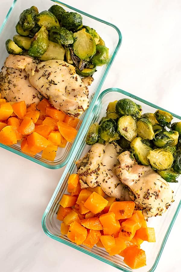 Two pyrex container filled with meal prepped sheet pan dijon mustard chicken and vegetables ( brussel sprouts and butternut squash)