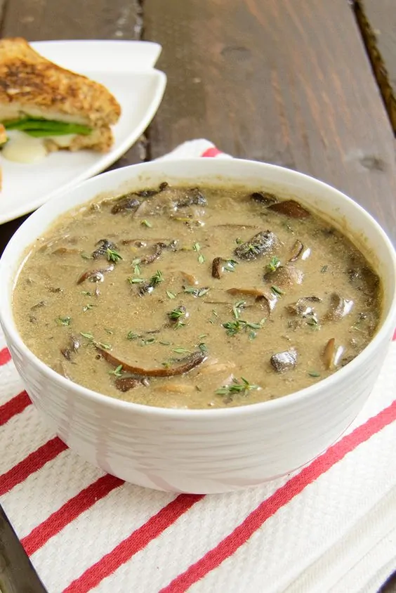 Large white bowl of dairy free mushroom soup over a red and white striped napkin