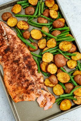 Cajun salmon sheet pan meal on the sheet pan with part of the salmon flaked away to show texture
