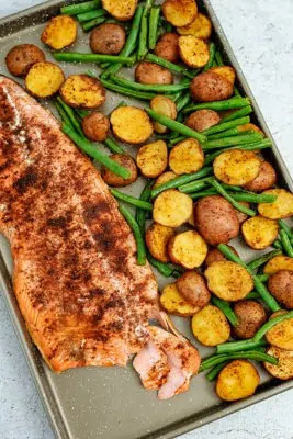 Cajun salmon sheet pan meal on the sheet pan with part of the salmon flaked away to show texture