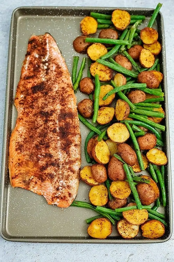 Sheet pan filled with cajun salmon sheet pan meal with an entire salmon fillet, potatoes and green beans