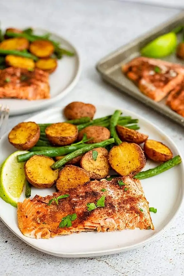 Close up of a plate of cajun salmon sheet pan dinner with the sheet pan in the background