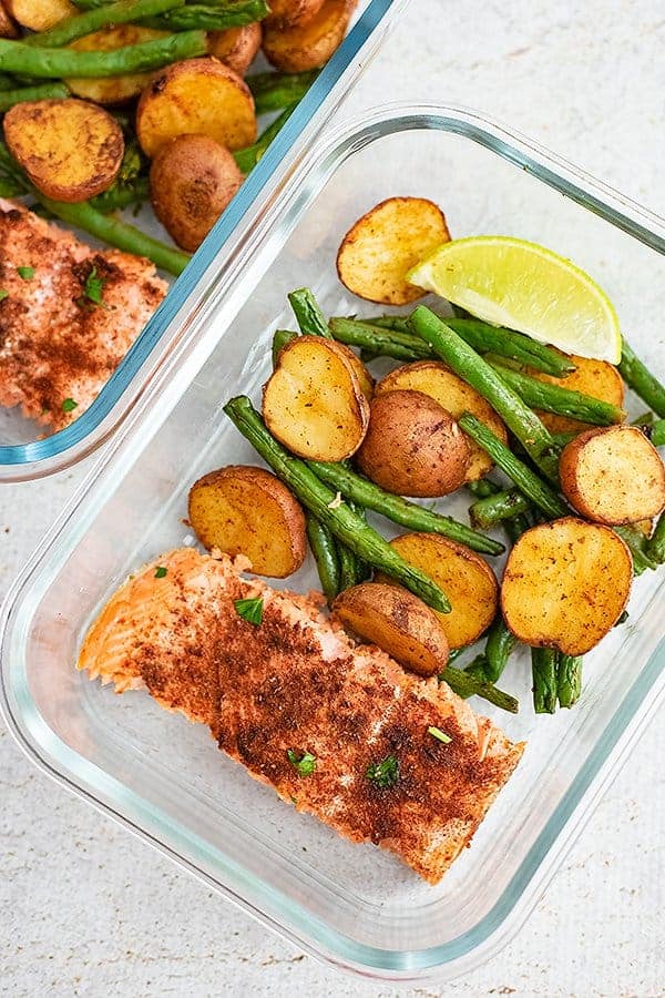 Glass tupperware filled with cajun salmon sheet pan meal ingredients (salmon, green beans and potatoes)