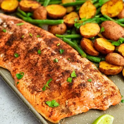 Close up of Sheet pan filled with cajun salmon sheet pan meal with an entire salmon fillet, potatoes and green beans