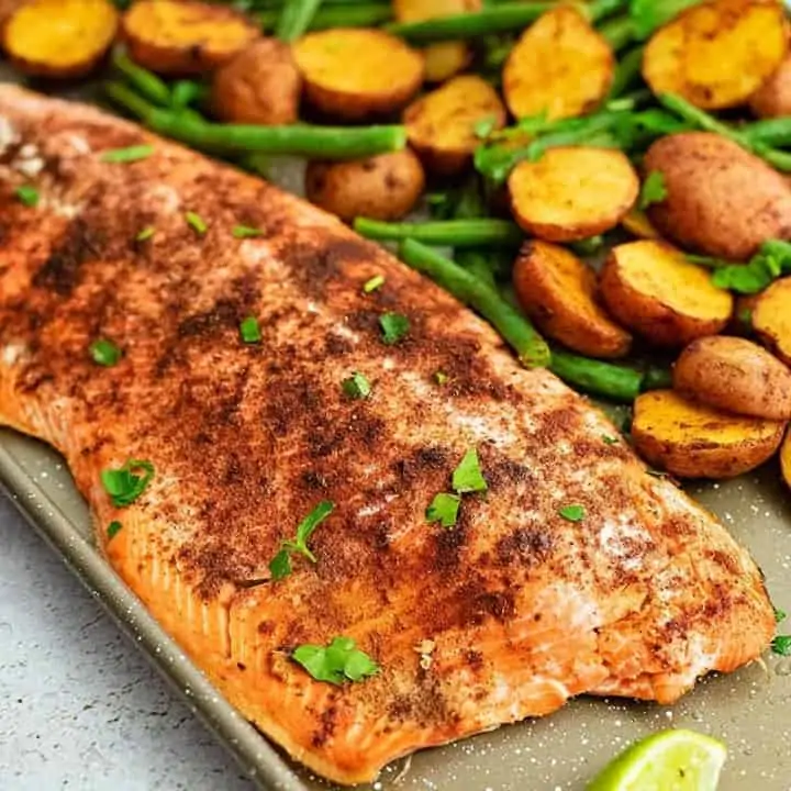Close up of Sheet pan filled with cajun salmon sheet pan meal with an entire salmon fillet, potatoes and green beans