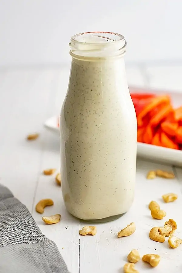 Close up on the bottle of vegan ranch dressing. Veggies on a platter in the background