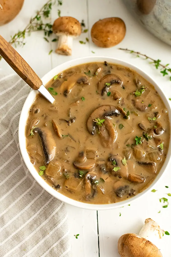 Bowl of easy vegan mushroom soup with a wooden spoon in the bowl.