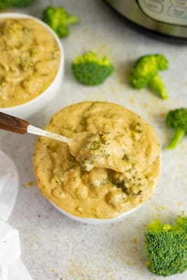 Overhead shot of a bowl of broccoli cauliflower soup with a spoon taking a spoonful of the soup.