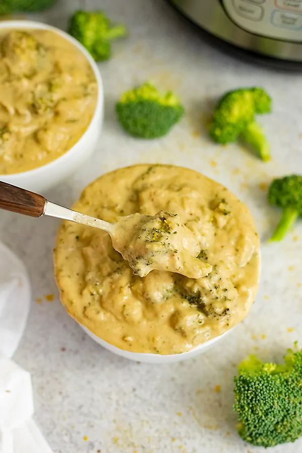 Overhead shot of a bowl of broccoli cauliflower soup with a spoon taking a spoonful of the soup. 
