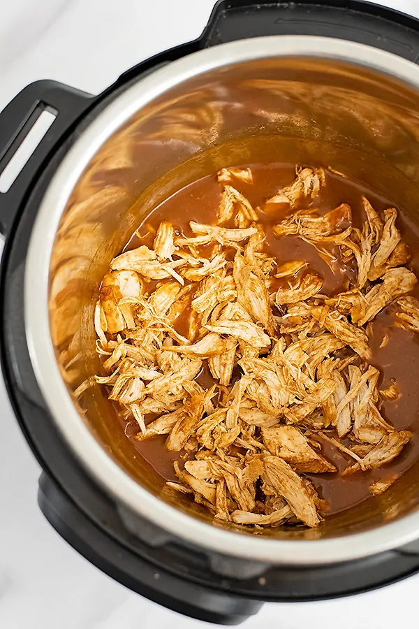 Instant pot BBQ chicken in the instant pot before the shredded chicken has been stirred with the thicken sauce