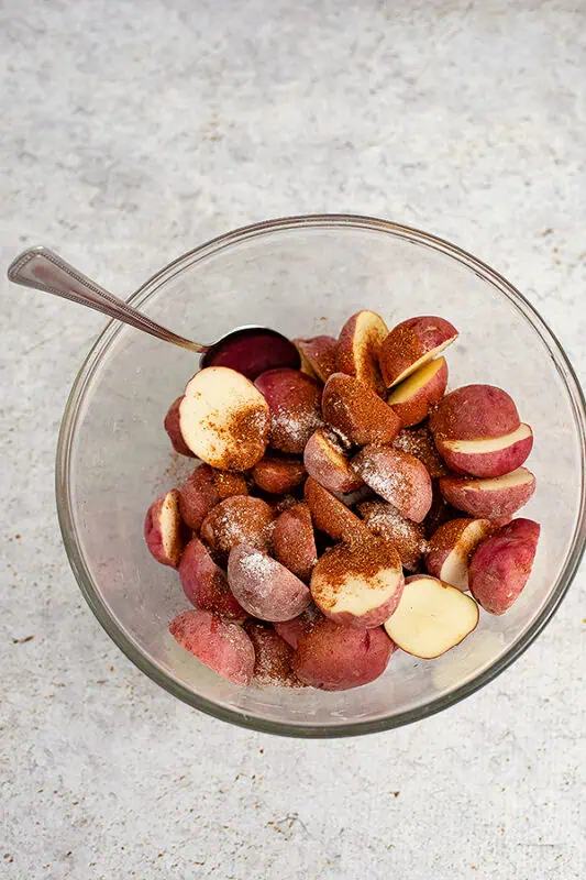 Glass bowl filled with potatoes, topped with cajun seasoning.