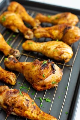 Baked chicken drumsticks right out of the oven over a baking sheet and baking rack.