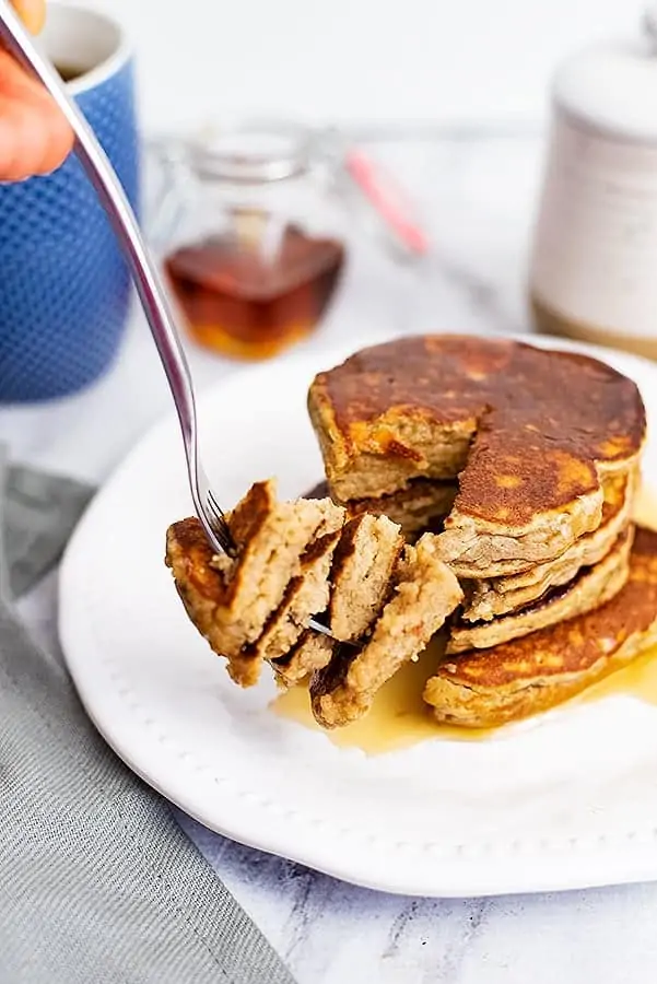 Fork holding a bite of protein pancakes just cut from the stack