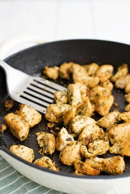 Overhead shot of a cast iron skillet filled with ranch chicken bites with a silver spatula in the pan with the chicken