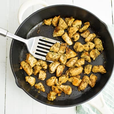 Overhead shot of a cast iron skillet filled with ranch chicken bites with a silver spatula in the pan with the chicken