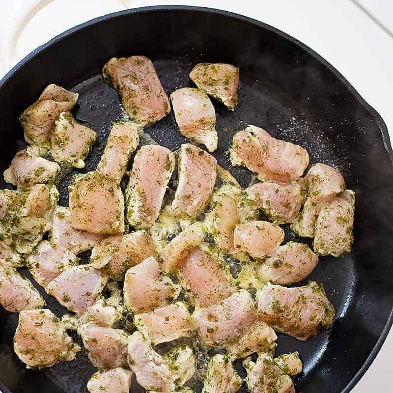Raw ranch chicken being cooked in a cast iron skillet