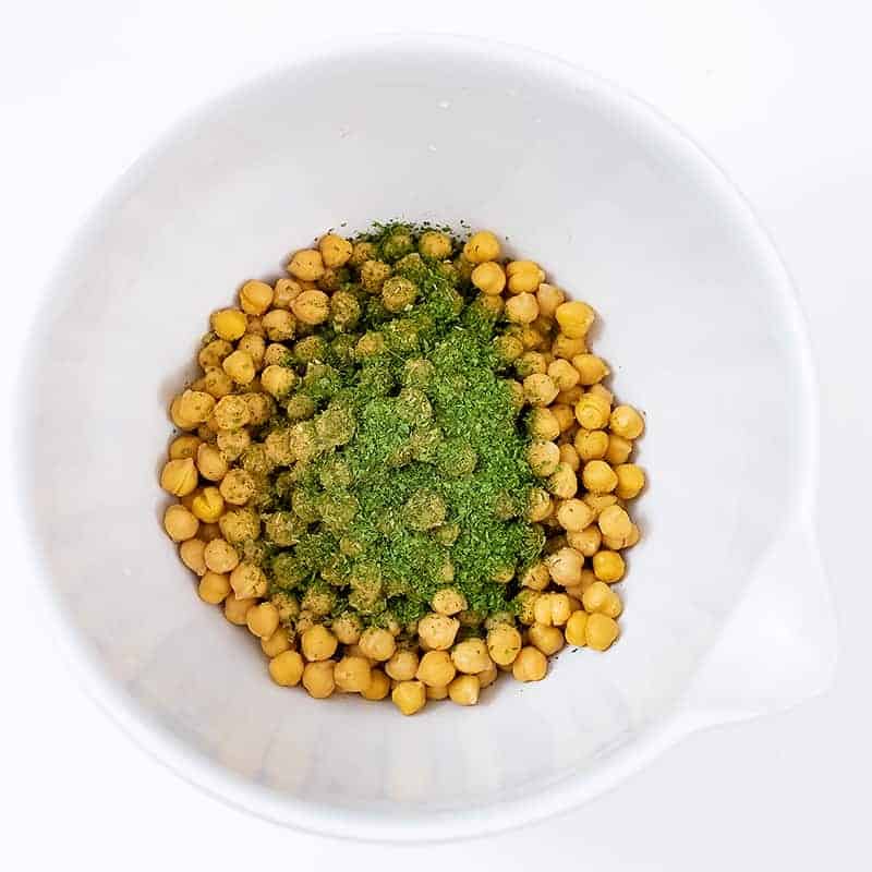 Large white bowl filled with ranch roasted chickpeas before cooking with the seasoning on top of the chickpeas before stirring