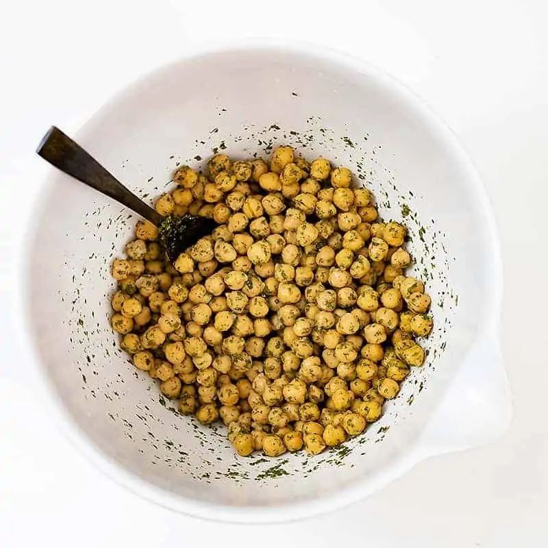 Large white bowl filled with ranch roasted chickpeas before cooking with the seasoning coating the chickpeas