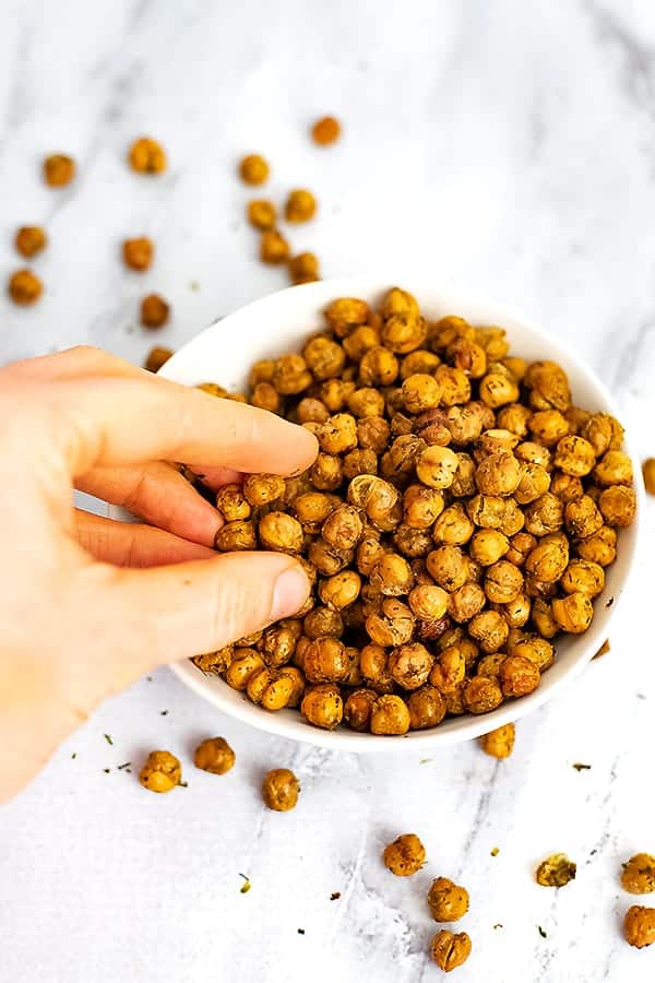 Hand reaching into a bowl of ranch roasted chickpeas