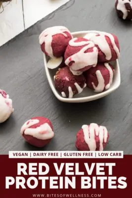 Small bowl filled with red velvet protein bites surrounded by additional protein bites. Pinterest text on the bottom