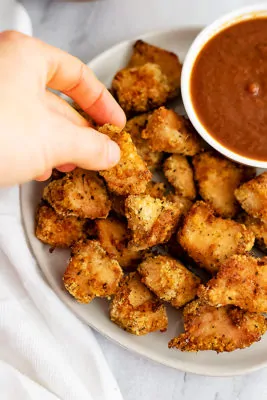 Hand coming from the top left of the photo picking up an air fryer chicken nugget