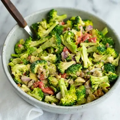 Overhead shot of a bowl filled with crunchy broccoli salad with lemon tahini dressing with a wooden spoon in the bowl
