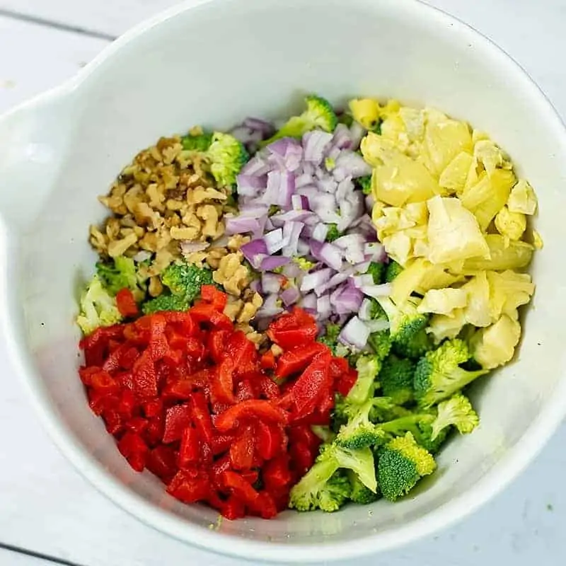 Overhead shot of a bowl filled with crunchy broccoli salad ingredients in the bowl before stirring in the dressing