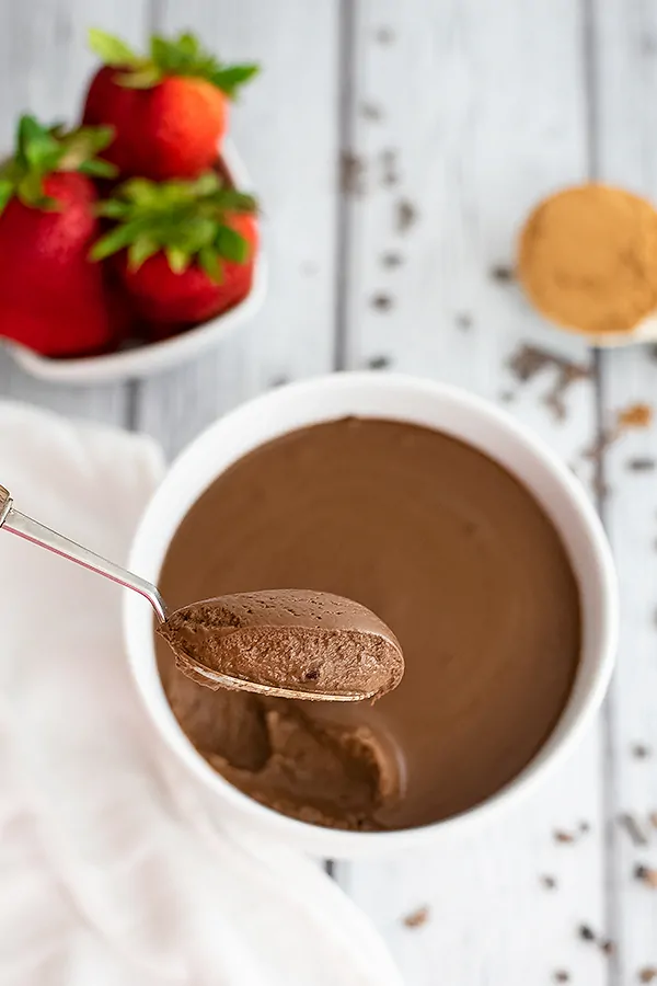 Spoonful of the chocolate protein pudding after refrigeration Strawberries in background 