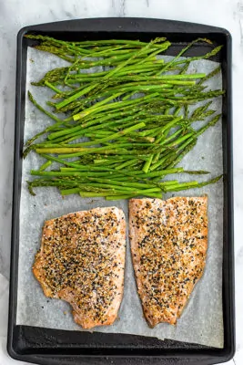 Sheet pan with asparagus on the top and everything bagel salmon on the bottom of the pan.