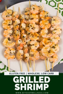 Large plate filled with grilled shrimp on wooden skewers. Pinterest text on the bottom