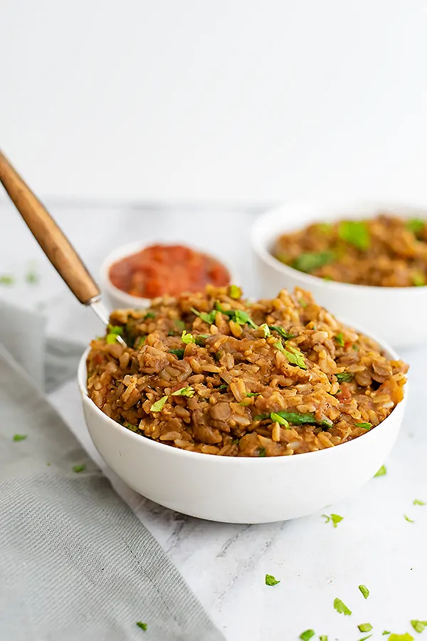 Bowl of Mexican Rice and Lentils with a wooden handled spoon