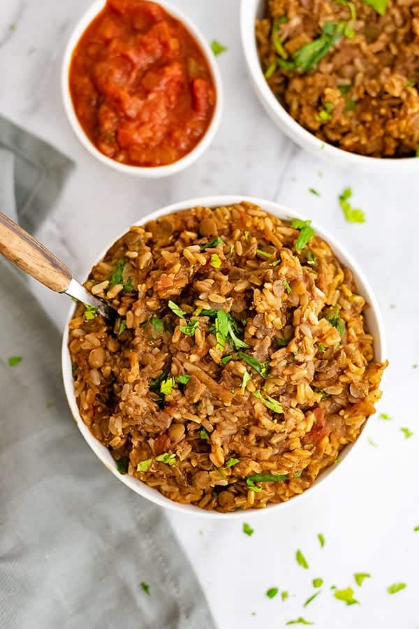 Bowl of Mexican Rice and Lentils with a wooden handled spoon