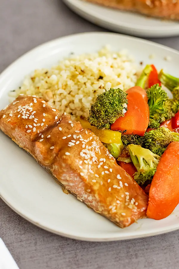 Baked teriyaki salmon, veggies and cauliflower rice on a large white plate.